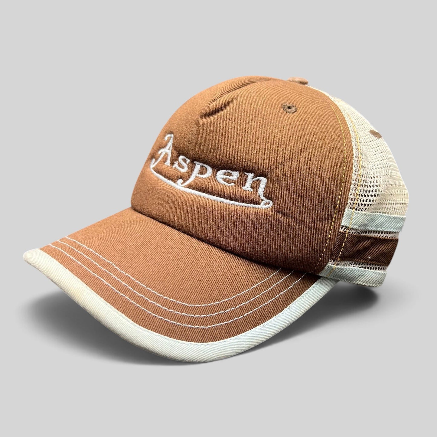 Raree Finds brown Aspen trucker hat with white script embroidery, structured cotton front, and breathable mesh back.
