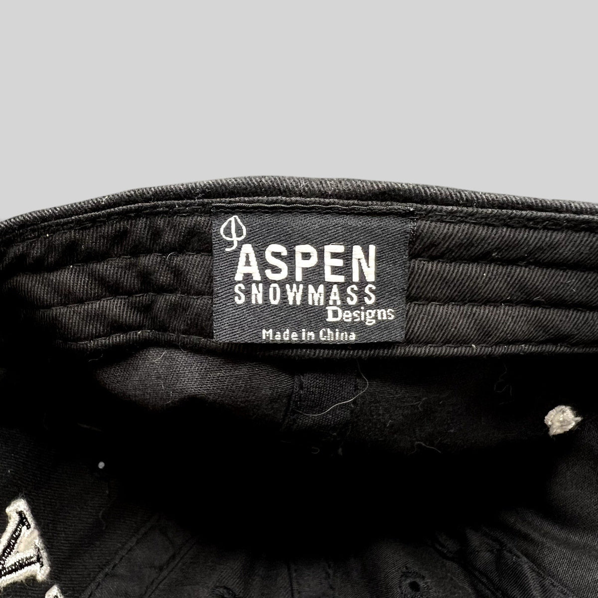 Raree Finds black cotton Aspen Snowmass Designs hat interior label with white embroidered text