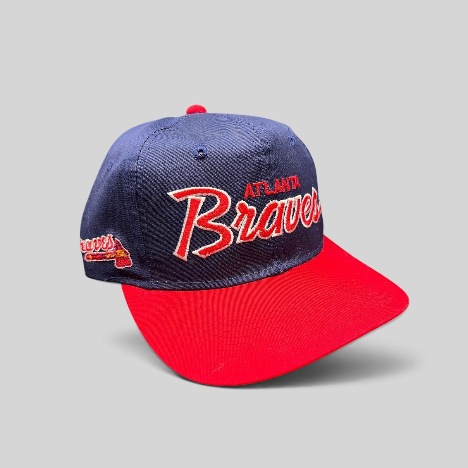 Raree Finds vintage 90s Atlanta Braves snapback hat with navy crown, red brim, and raised script embroidery.