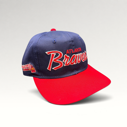 Raree Finds vintage 90s Atlanta Braves snapback hat with navy crown, red brim, and raised script embroidery.