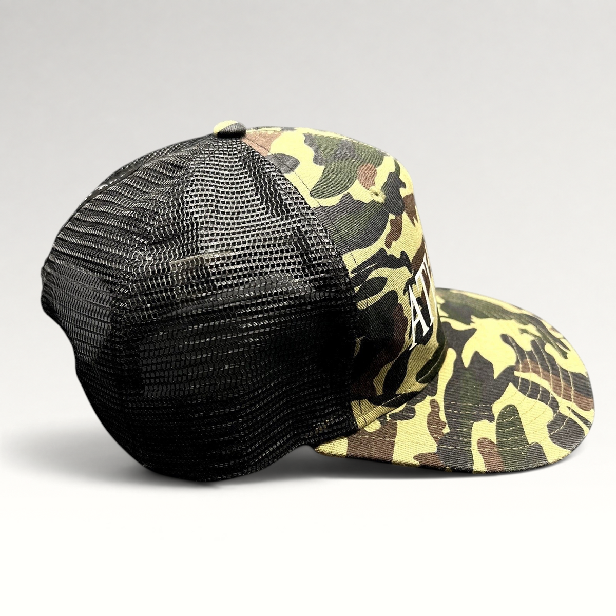 Raree Finds ATLWOOD woodland camo mesh trucker snapback hat with white front embroidery and black rear mesh panels.