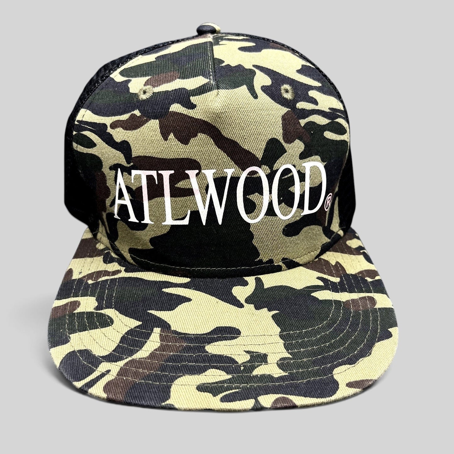 Raree Finds ATLWOOD woodland camo trucker hat with white front embroidery, black mesh back, and flat brim.