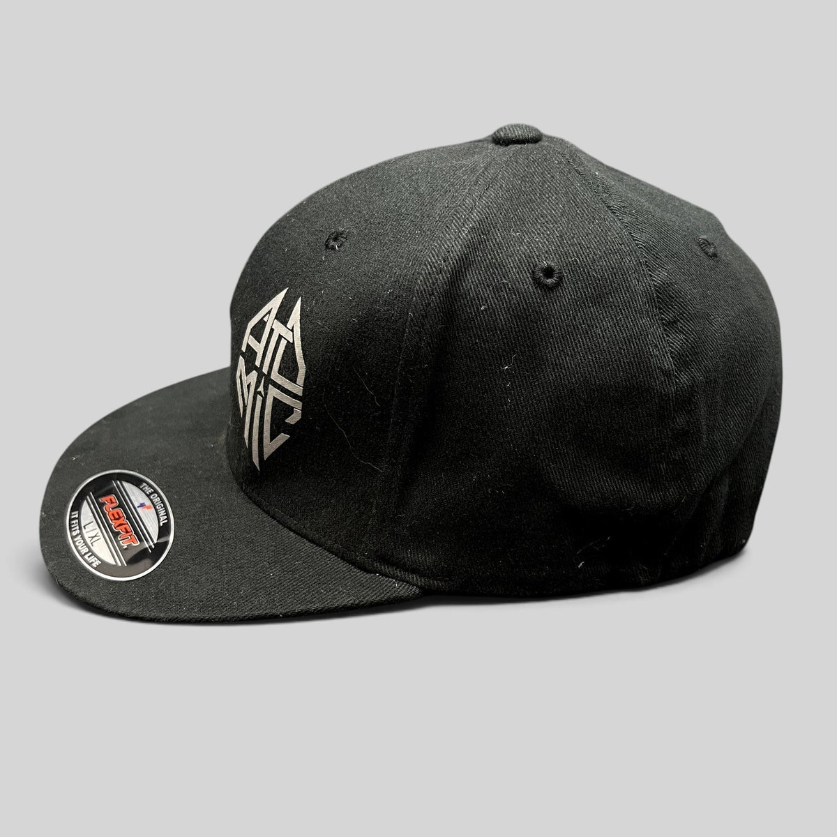 Raree Finds black Atomic Skis FlexFit cap with white embroidered logo and flat brim, side profile view.