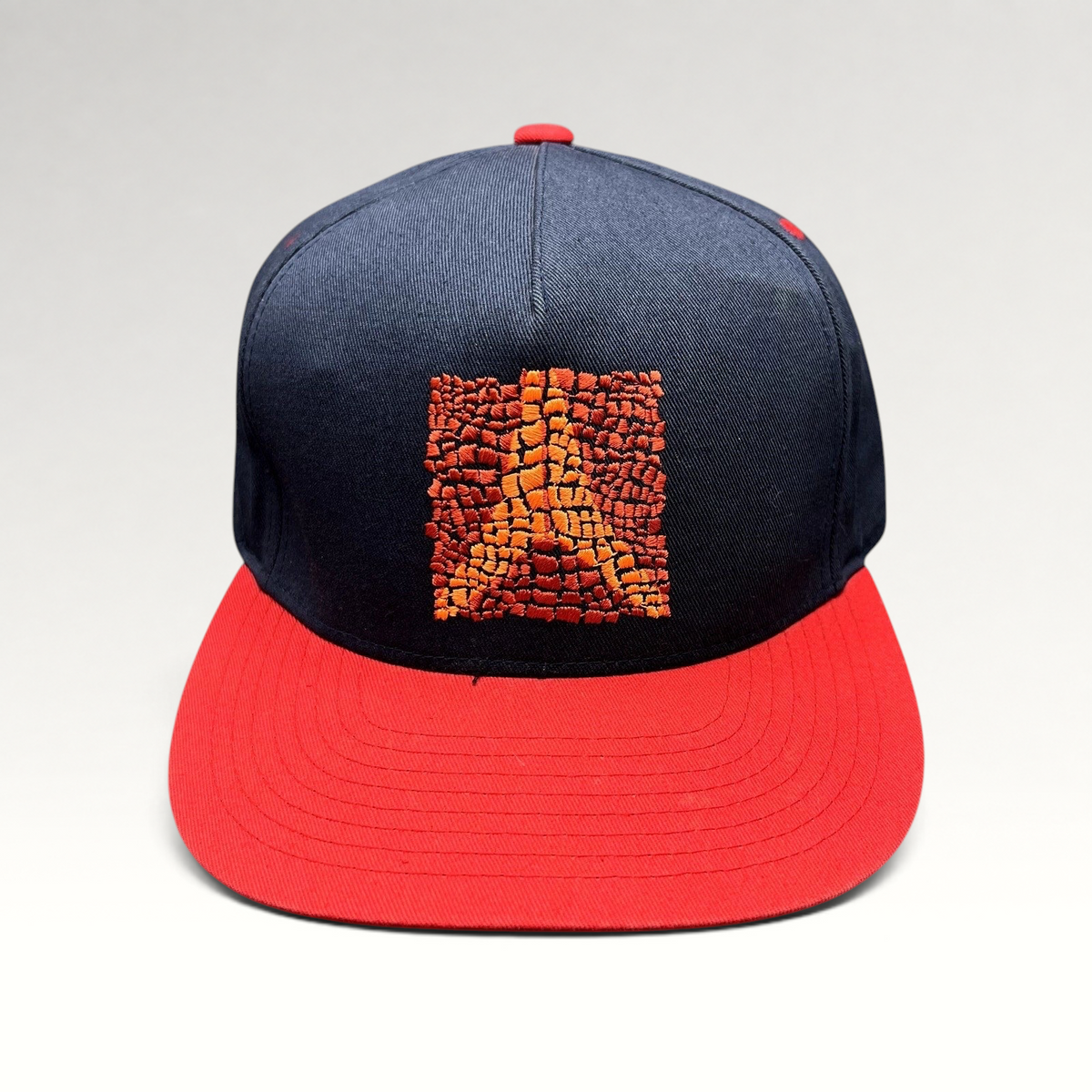 Raree Finds Atomic Skis navy snapback hat with a red flat brim and embroidered orange Eiffel Tower mosaic graphic
