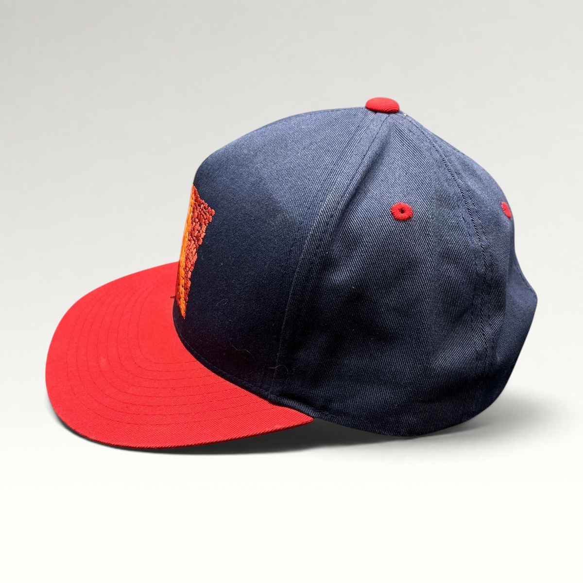 Raree Finds Atomic Skis snapback hat with navy crown, red flat brim, and embroidered Eiffel Tower mosaic graphic.
