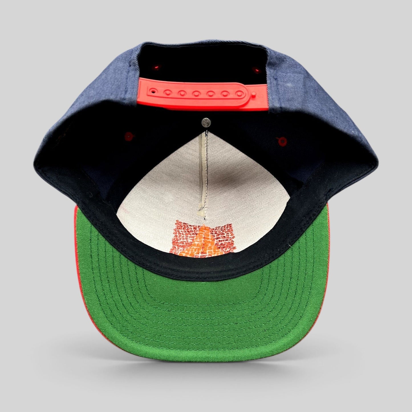 Raree Finds Atomic Skis snapback hat showing the green undervisor, red snap closure, and interior embroidery detail.