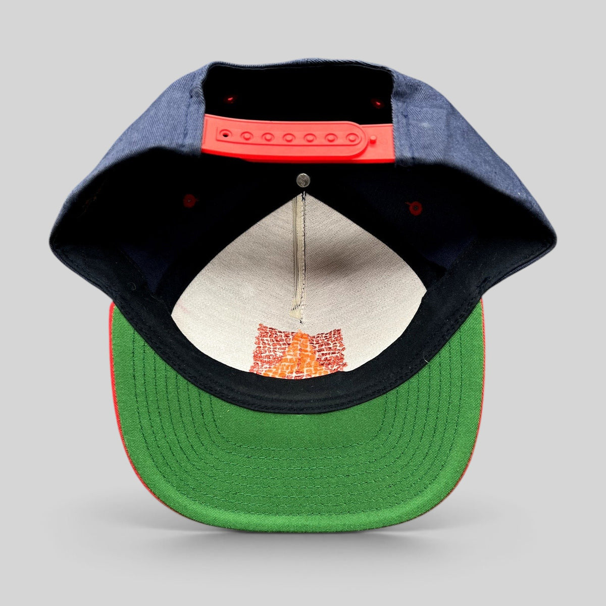 Raree Finds Atomic Skis snapback hat showing the green undervisor, red snap closure, and interior embroidery detail.