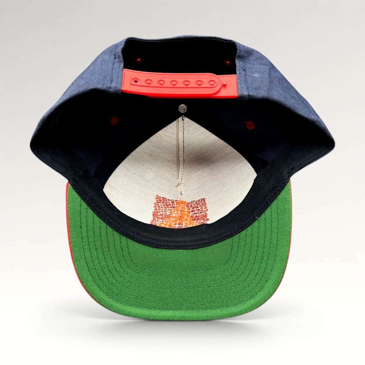 Raree Finds Atomic Skis snapback hat showing the green undervisor, red snap closure, and interior embroidery detail.