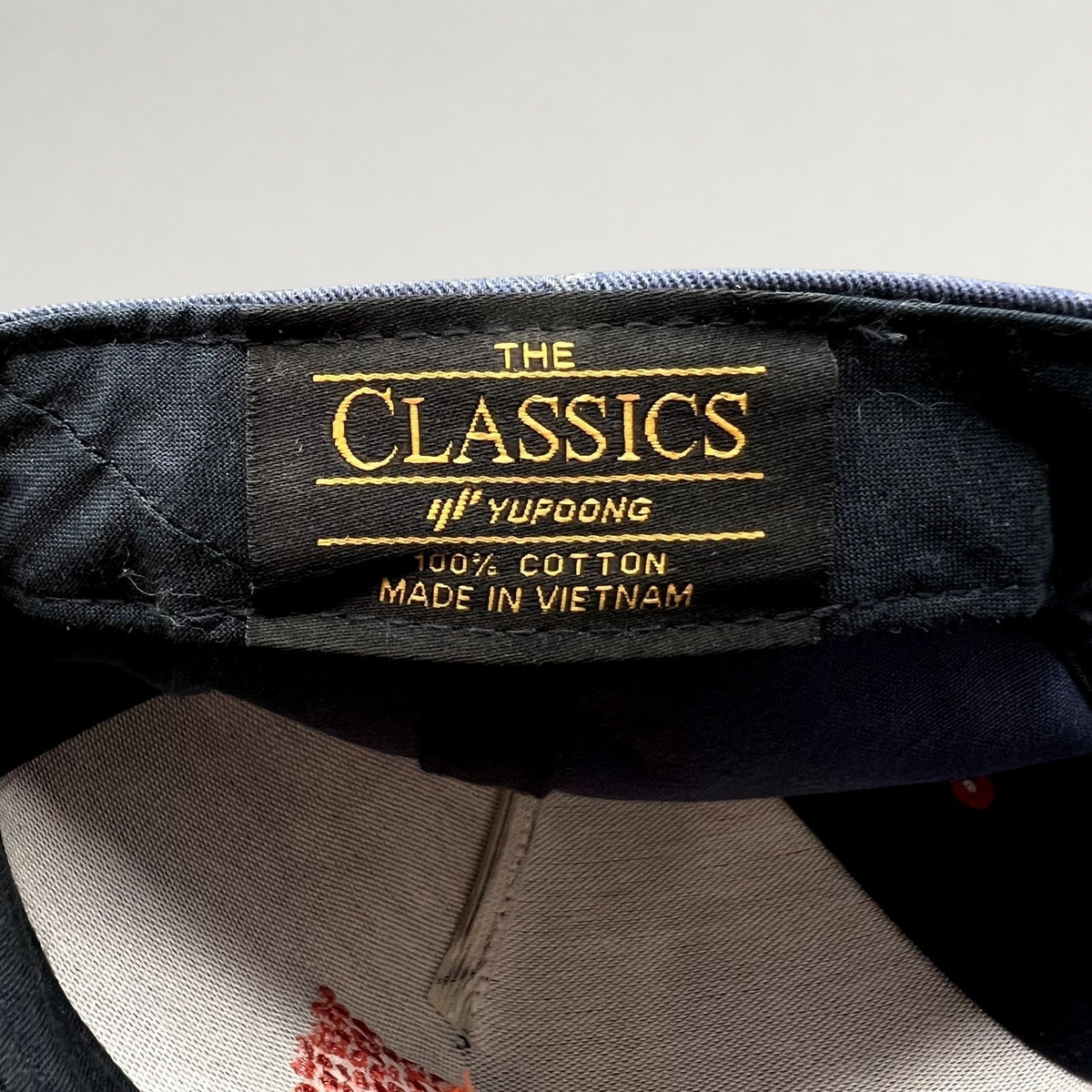 Raree Finds Atomic Skis snapback interior label showing Yupoong The Classics branding and 100% cotton material tag