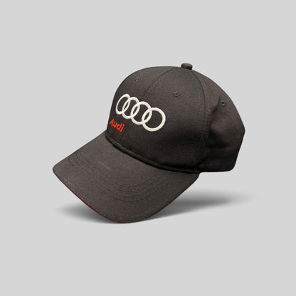 Raree Finds black cotton twill Audi strapback hat with white embroidered rings and red Audi logo on a dark background