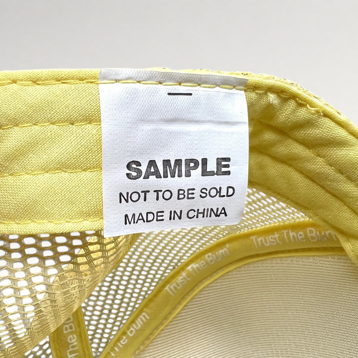 Raree Finds Baby Bum trucker hat interior tag reading Sample Not To Be Sold inside yellow mesh snapback cap