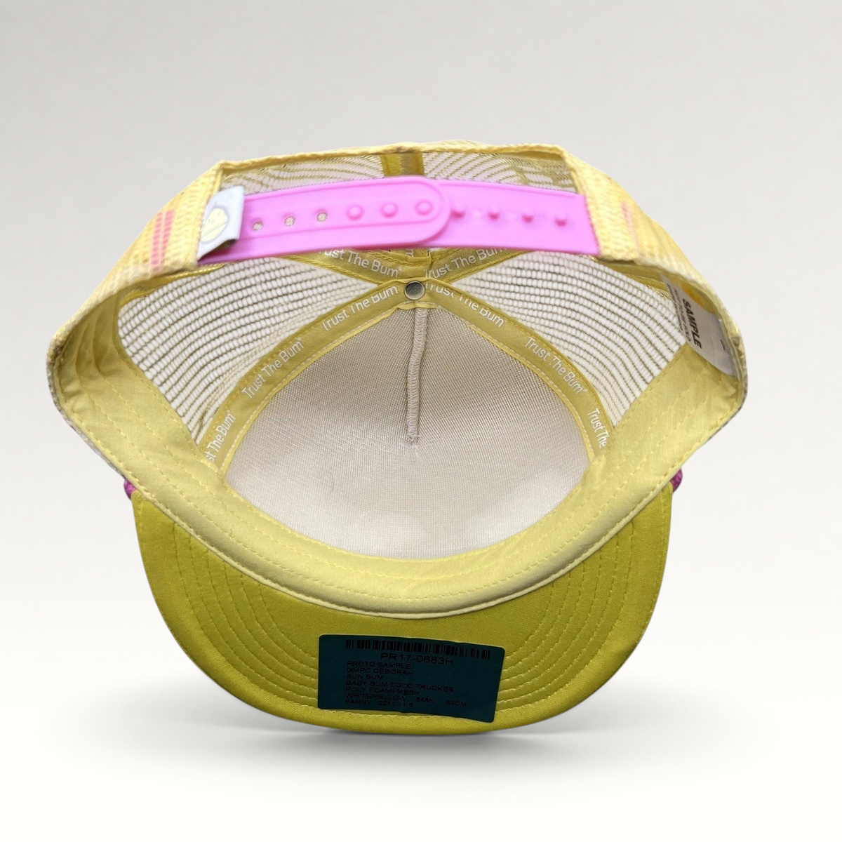 Raree Finds Baby Bum prototype trucker hat interior showing yellow mesh, pink snapback closure, and sample tags.