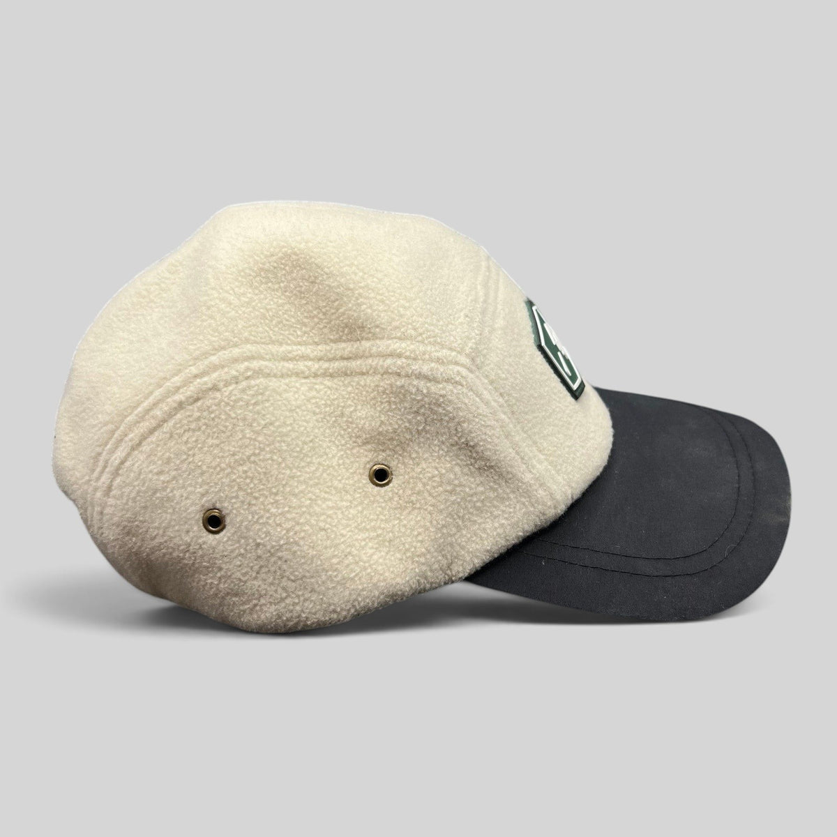 Raree Finds Baldface strapback hat with a cream fleece crown, black bill, and rubber logo patch, side profile view.