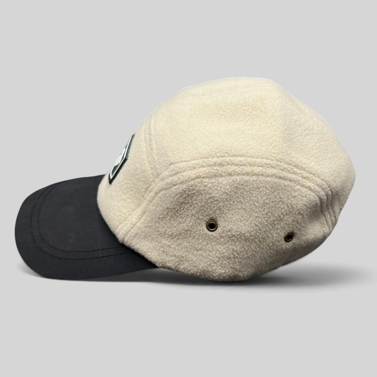 Raree Finds Baldface strapback hat with a cream fleece crown, black bill, and rubber logo patch, side profile view.
