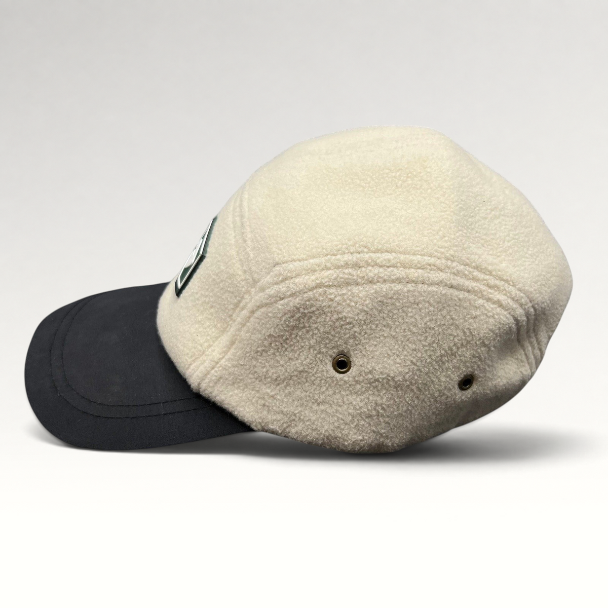 Raree Finds Baldface strapback hat with a cream fleece crown, black bill, and rubber logo patch, side profile view.