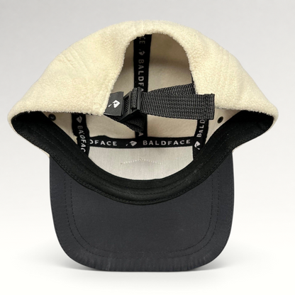 Raree Finds Baldface strapback hat featuring a cream fleece crown, black bill, and adjustable nylon clip closure.