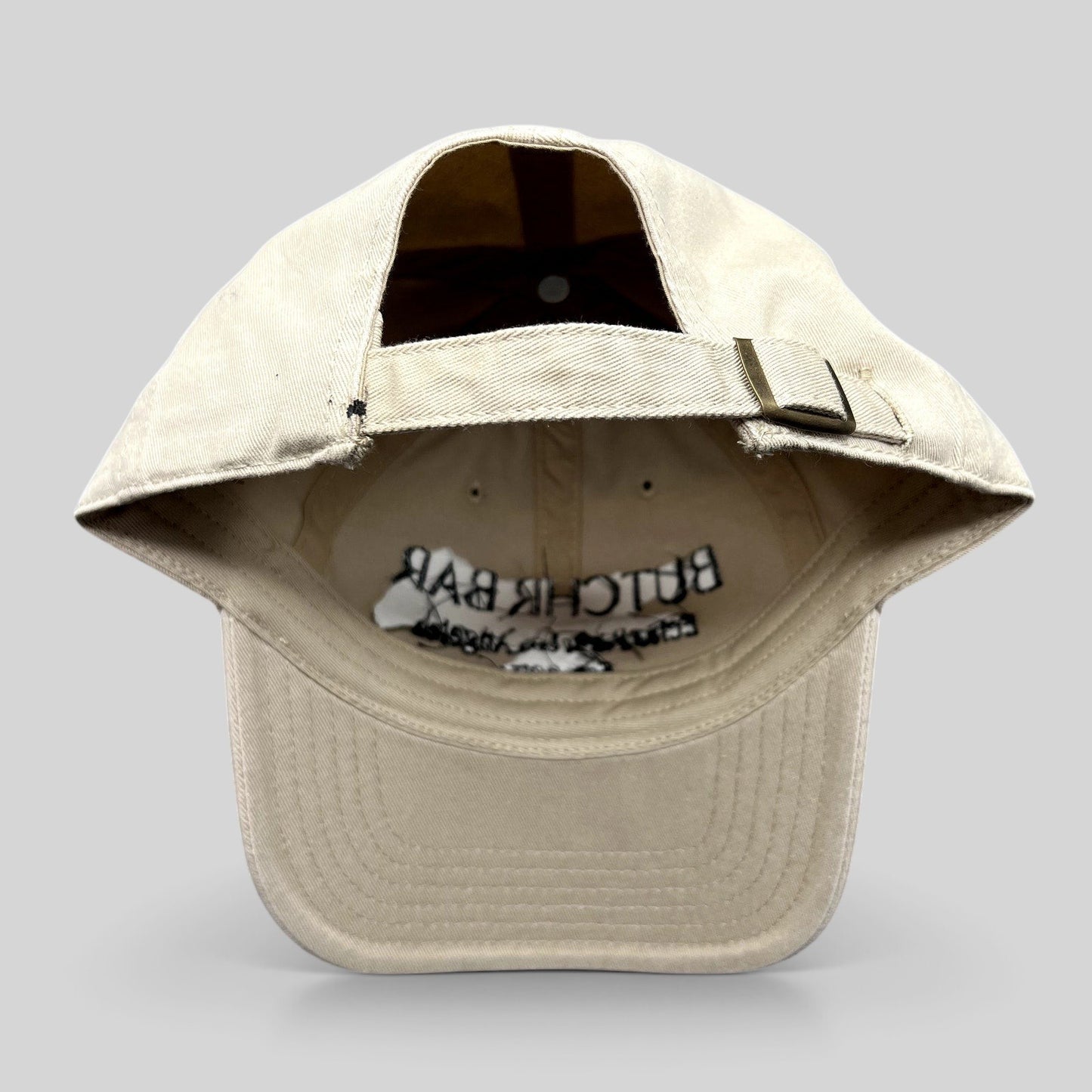 Raree Finds beige cotton twill strapback hat with adjustable brass buckle and interior Butchr Bar embroidery
