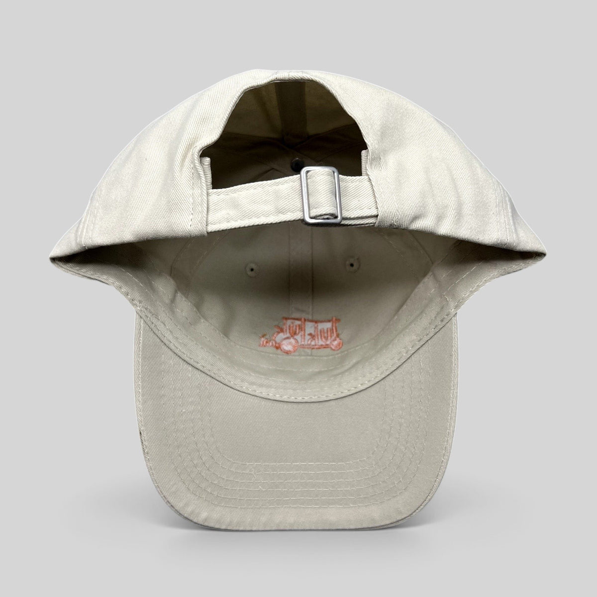 Raree Finds beige Tuk Tuk Thai strapback hat showing the adjustable metal buckle closure and interior branding