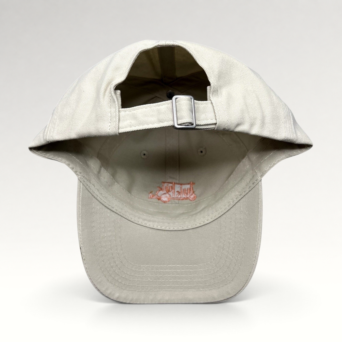 Raree Finds beige Tuk Tuk Thai strapback hat showing the adjustable metal buckle closure and interior branding