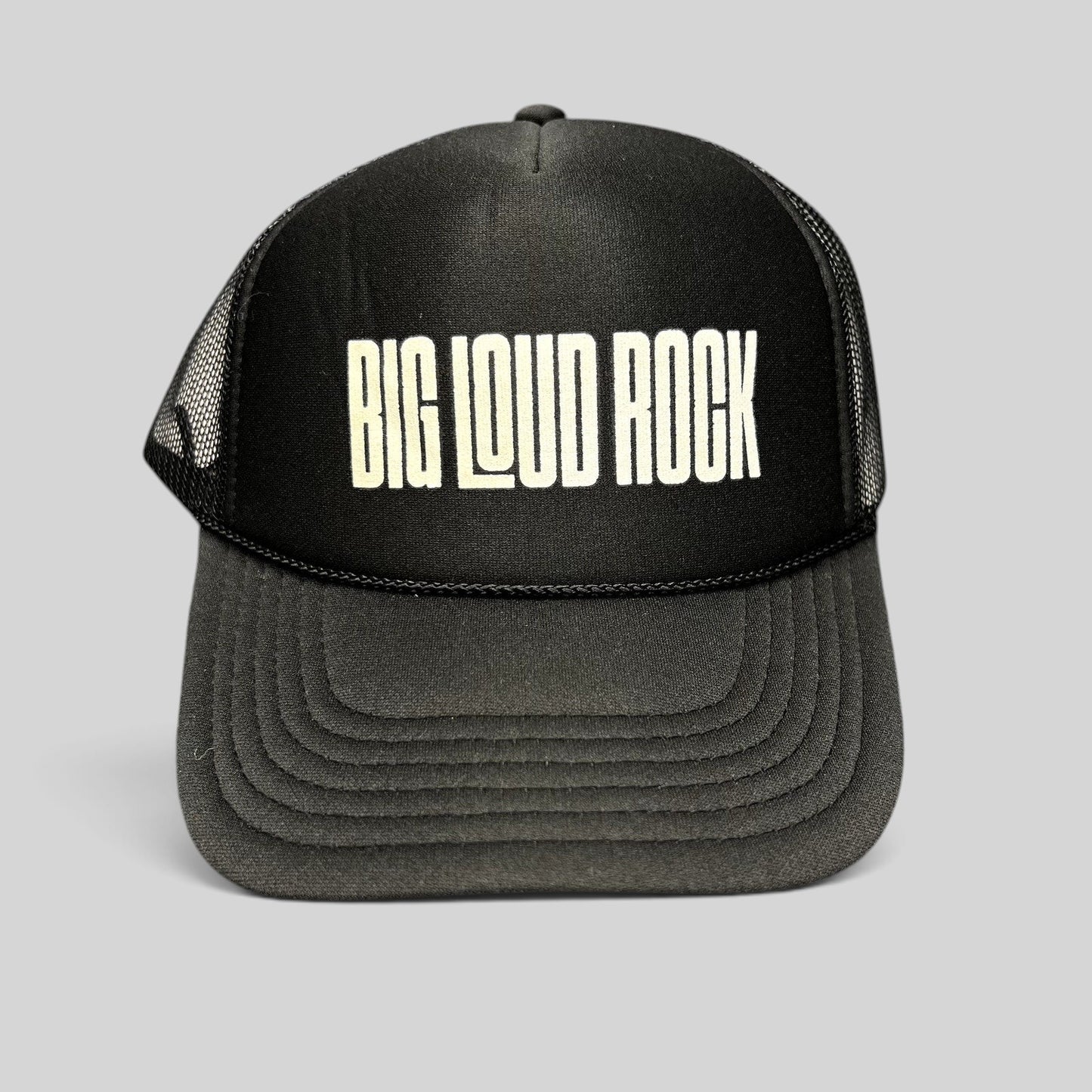 Raree Finds black Otto trucker hat with white BIG LOUD ROCK graphic, foam front, and breathable mesh back panels.