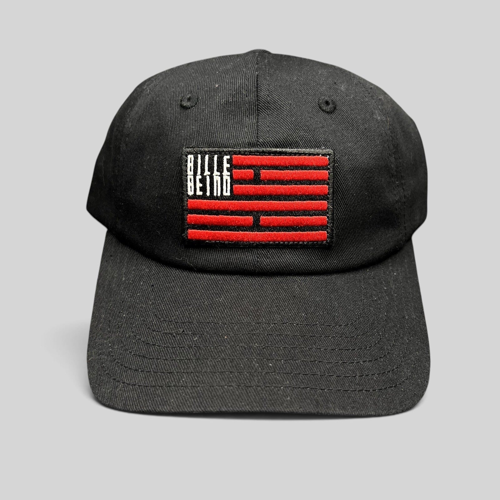 Raree Finds BilleBeino black strapback hat with a red embroidered flag logo patch and curved brim