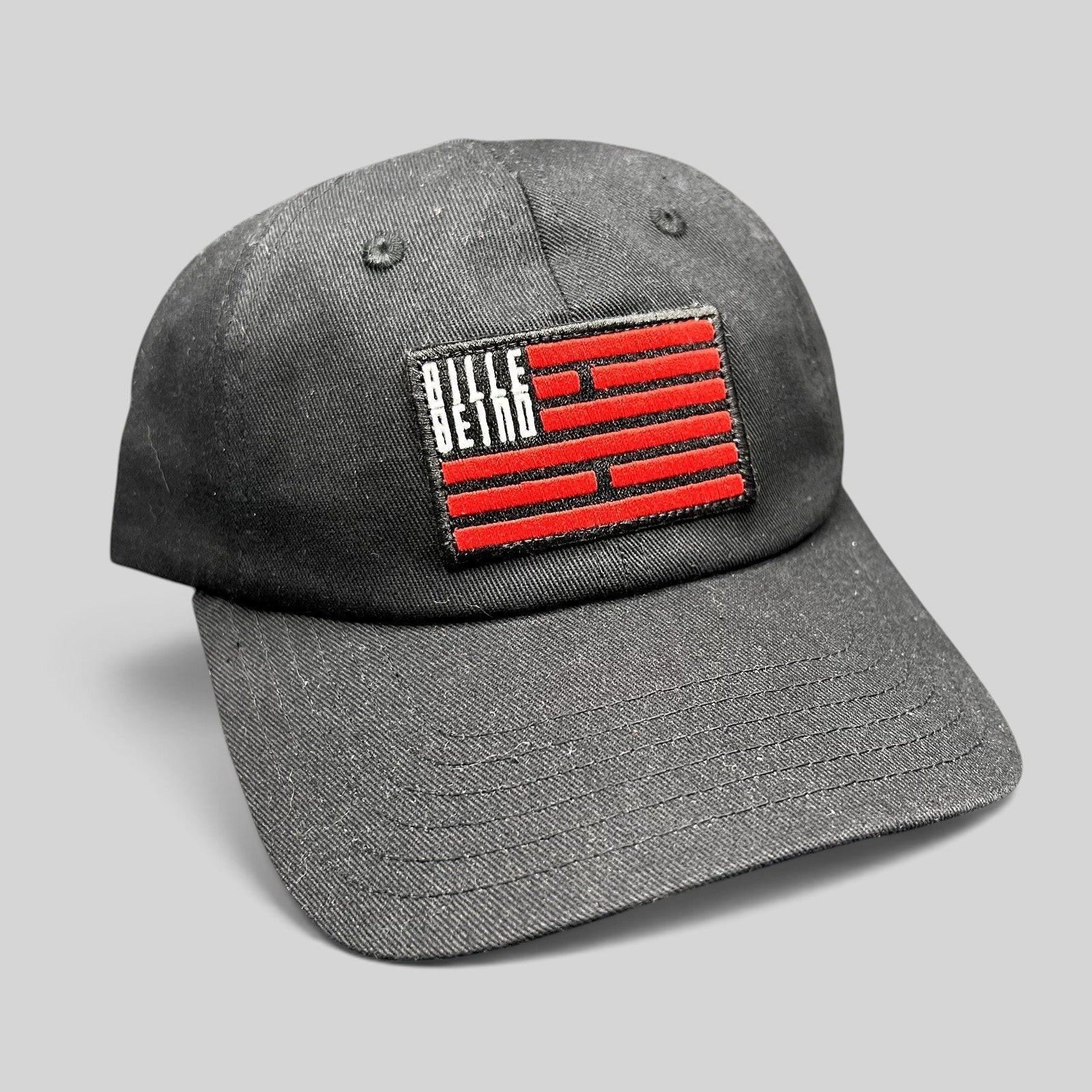 Raree Finds BilleBeino black strapback hat with a red embroidered geometric flag logo on the front crown