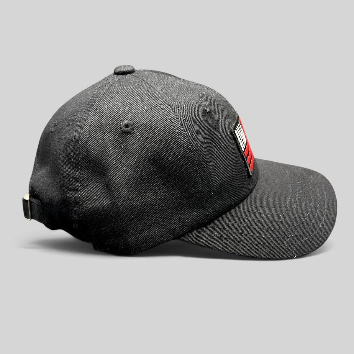 Raree Finds BilleBeino black strapback hat with red embroidered flag logo and adjustable metal buckle closure
