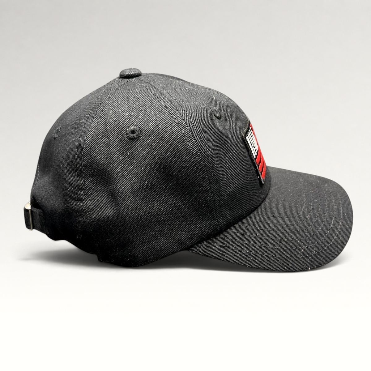 Raree Finds BilleBeino black strapback hat with red embroidered flag logo and adjustable metal buckle closure