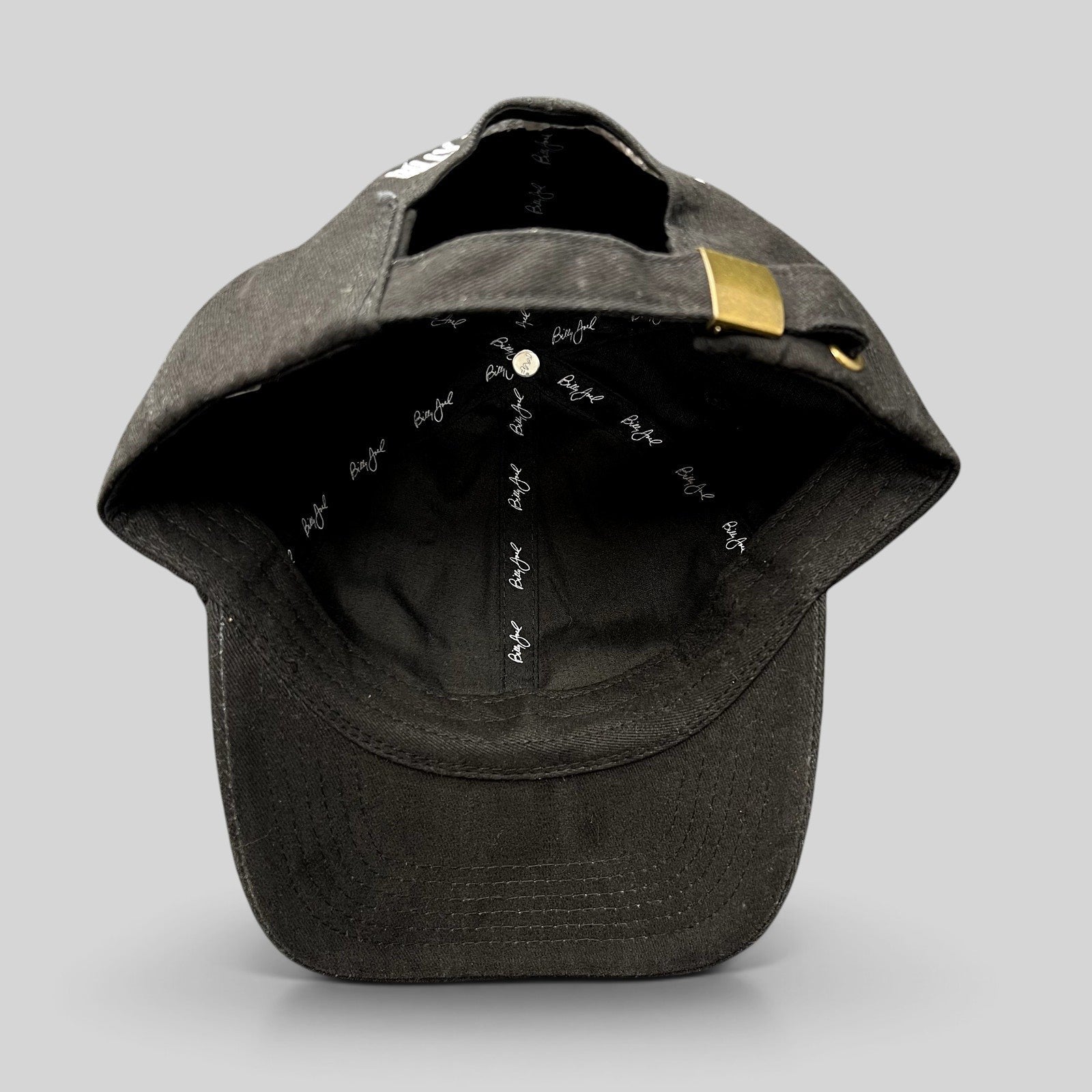 Raree Finds Billy Joel black strapback hat showing interior branded taping and brass buckle closure