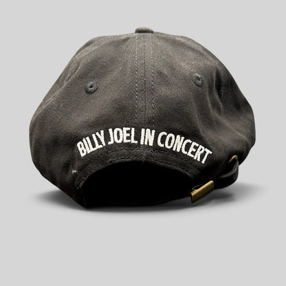 Raree Finds black Billy Joel In Concert strapback hat with white back embroidery and adjustable brass buckle closure.