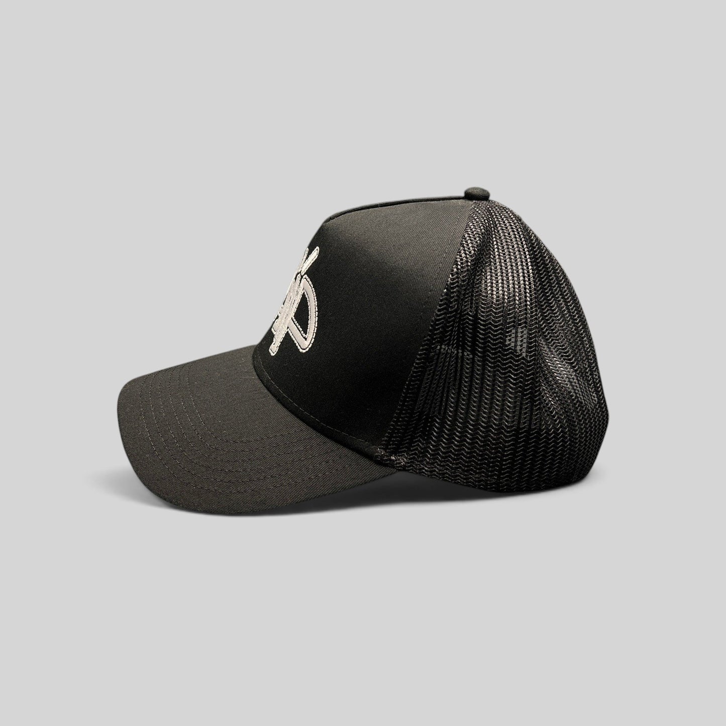 Raree Finds black mesh trucker hat with embroidered white AMP logo, structured crown, and adjustable snapback.