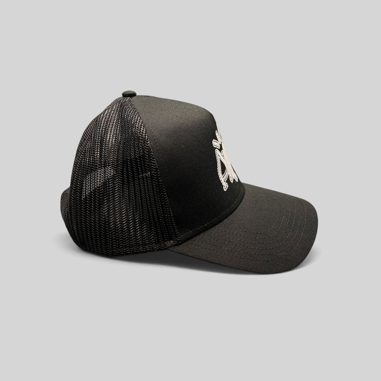 Raree Finds black mesh trucker hat with embroidered white AMP logo, featuring a structured crown and snapback closure.