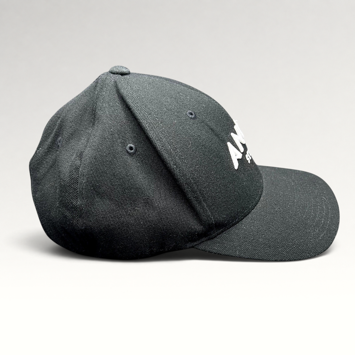 Raree Finds black Flexfit hat with white embroidered Angel Studios logo and curved brim, side profile view.