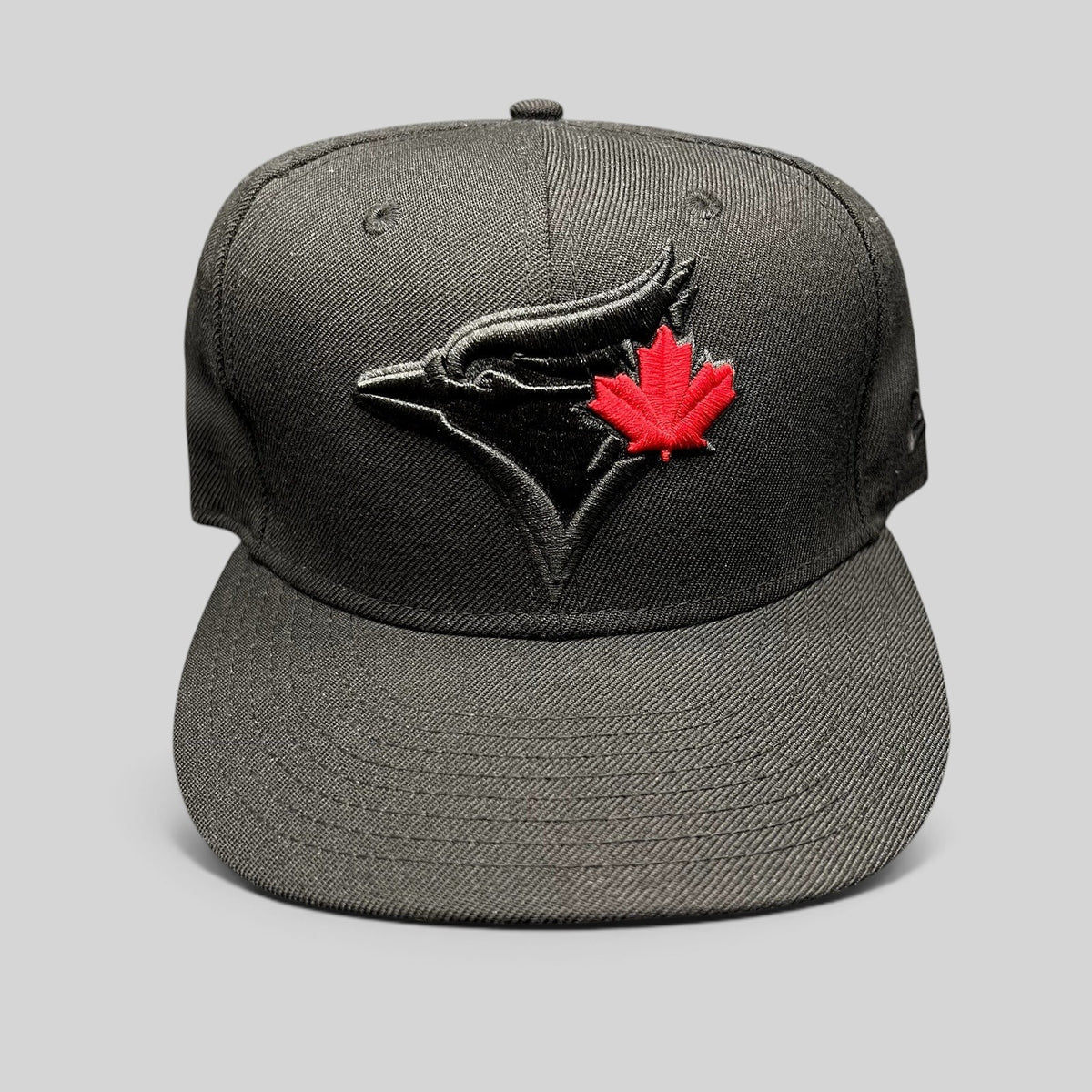 Raree Finds black New Era Toronto Blue Jays snapback hat with a raised tonal logo and a vibrant red maple leaf detail.