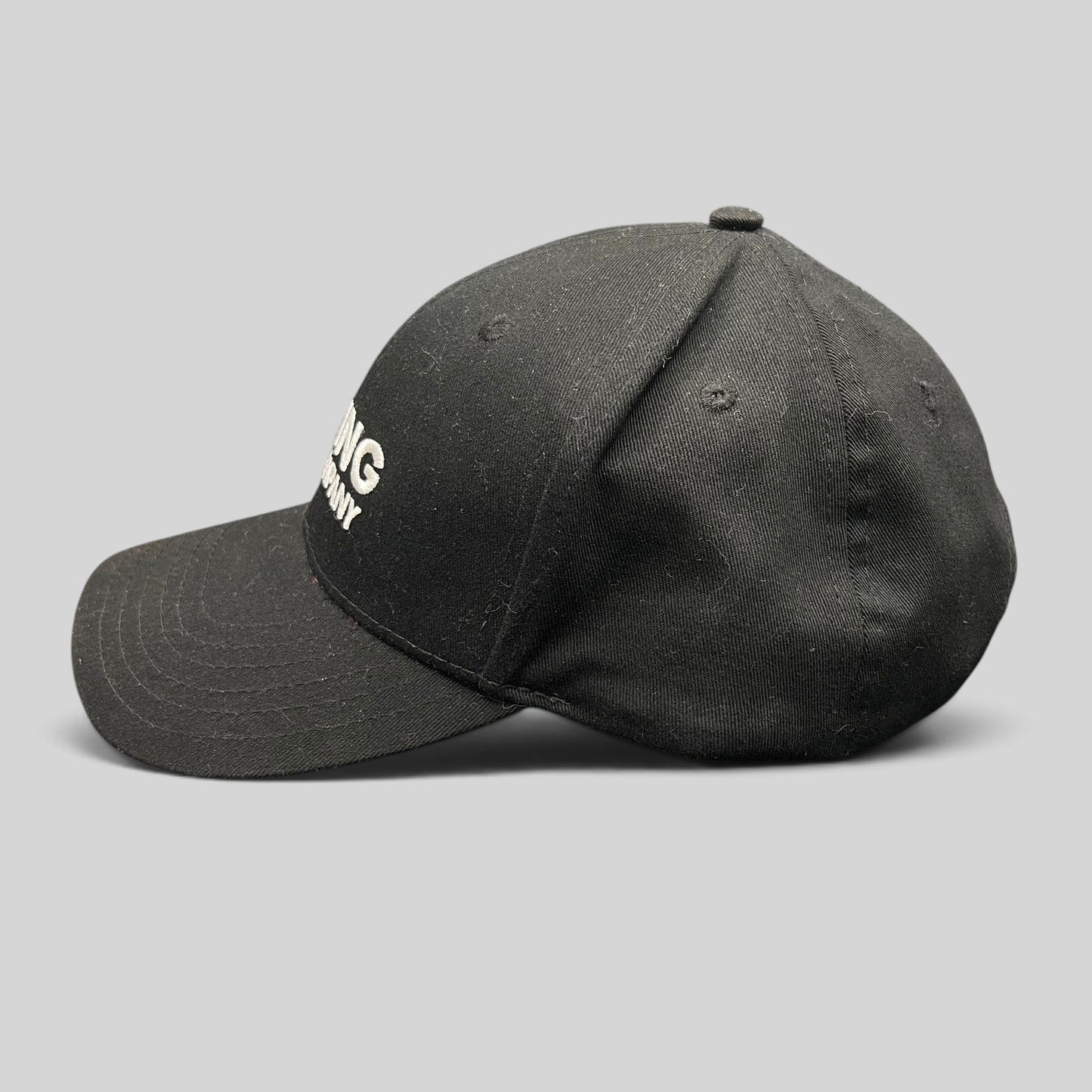 Raree Finds black The Boring Company strapback hat with white embroidered logo and curved brim, side profile view.