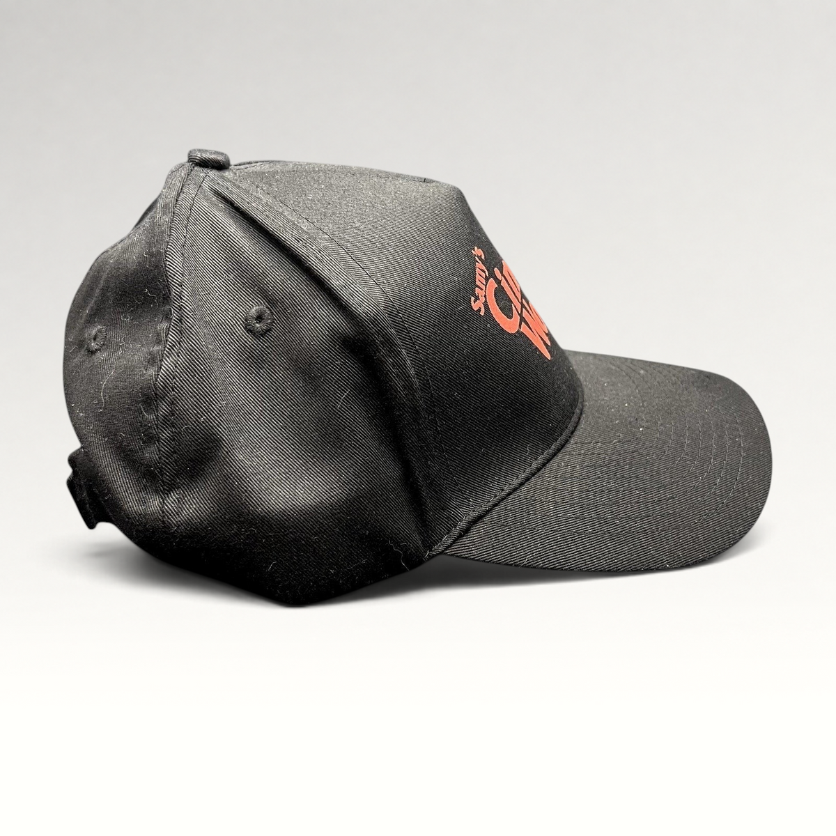 Raree Finds black cotton twill strapback hat with red Samy's CinemaWorks embroidery, side profile view.