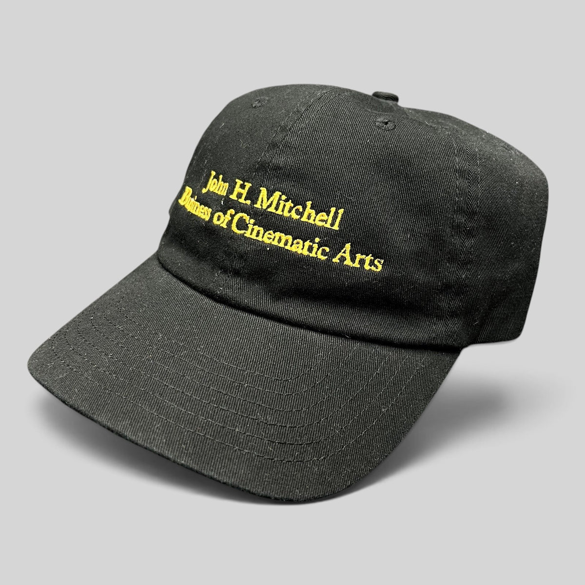 Raree Finds black cotton strapback hat with gold embroidered John H. Mitchell Business of Cinematic Arts lettering.