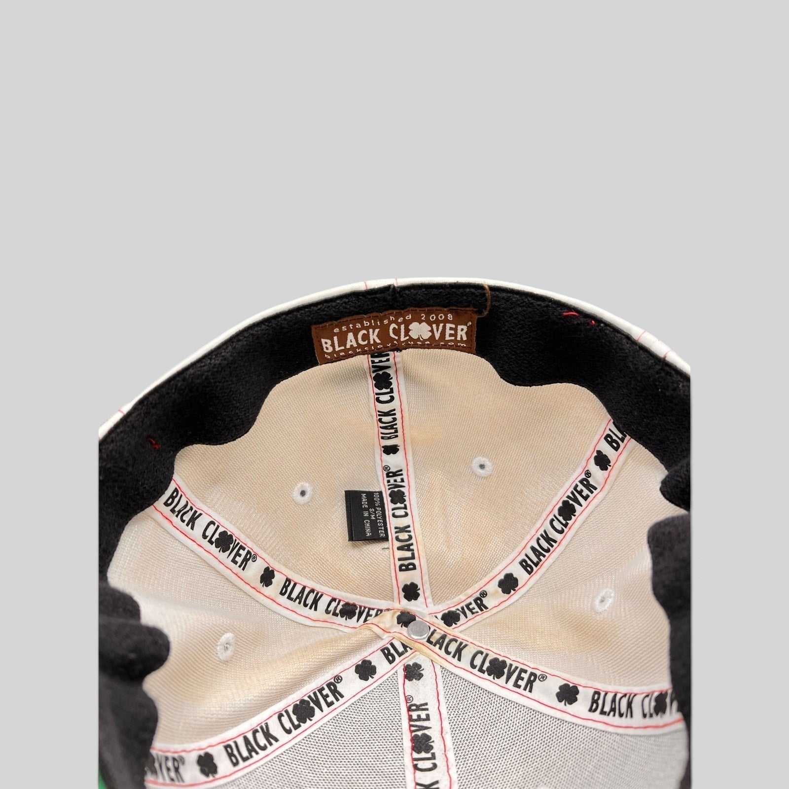 Interior view of a Raree Finds Black Clover cap showing branded seam tape and the established 2008 label
