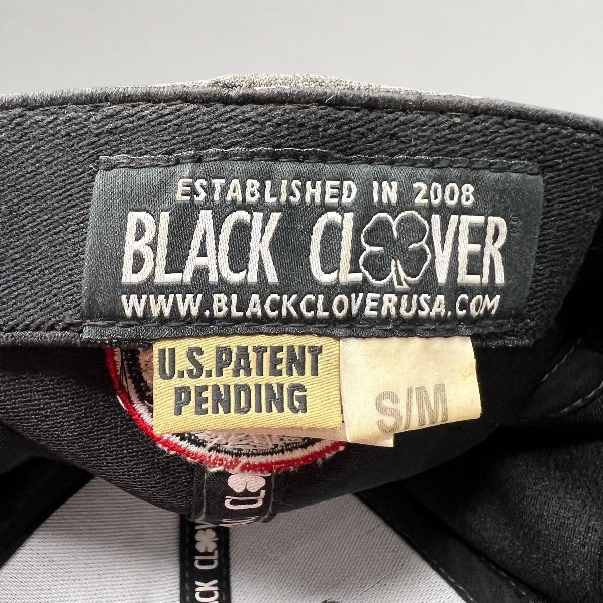 Raree Finds Black Clover cap interior label showing brand logo, patent pending status, and size S/M tag