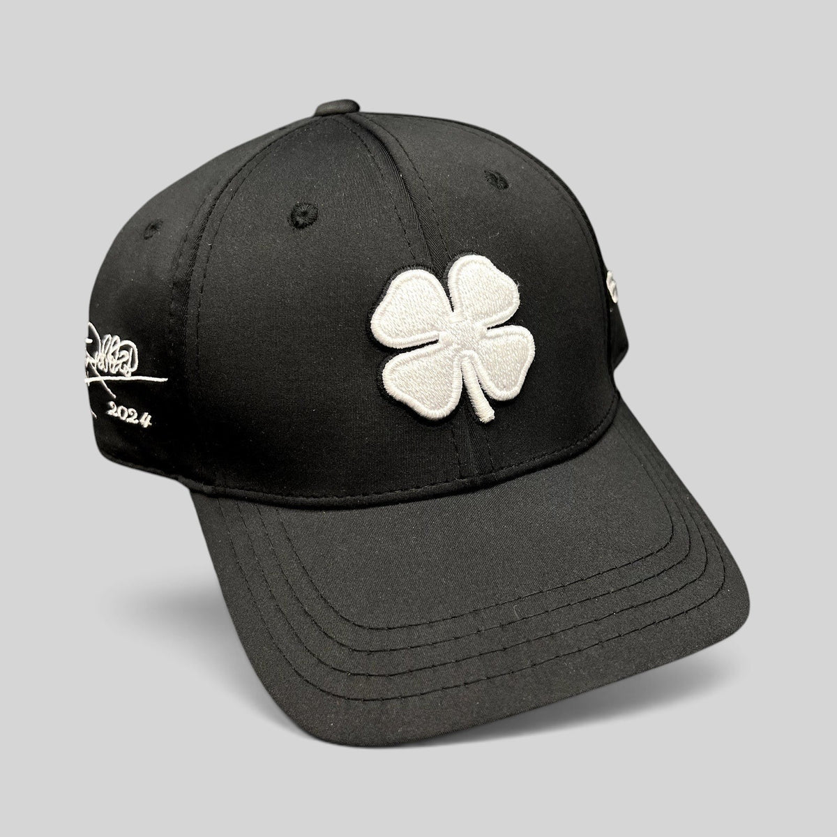 Raree Finds black snapback golf hat with white embroidered clover logo and Tony Robbins Blessed 2024 side detail.