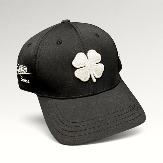 Raree Finds black snapback golf hat with white embroidered clover logo and Tony Robbins Blessed 2024 side detail.