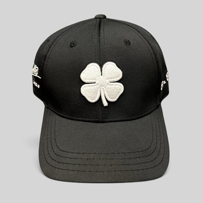 Raree Finds black snapback golf hat featuring a large white embroidered clover logo and Blessed 2024 side branding.
