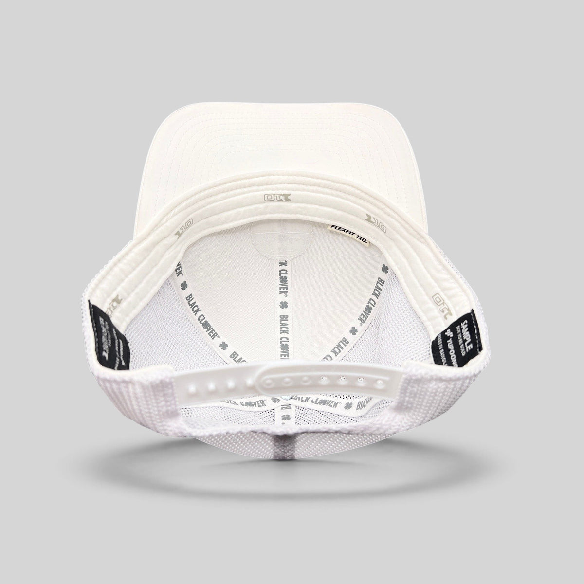 Raree Finds Black Clover white trucker hat interior view showing Yupoong Flexfit snapback and branded inner taping