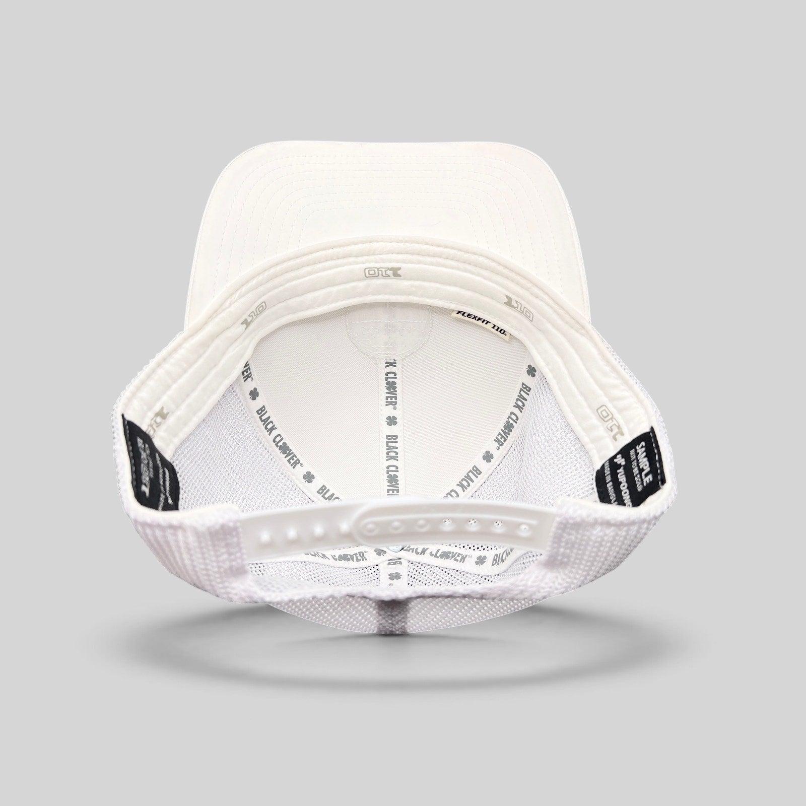 Raree Finds Black Clover white trucker hat interior view showing Yupoong Flexfit snapback and branded inner taping
