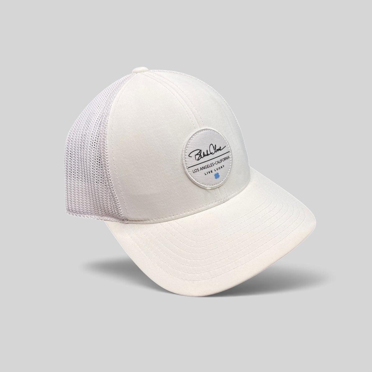 Raree Finds Black Clover white trucker hat with Live Lucky circular patch and blue clover detail on mesh back