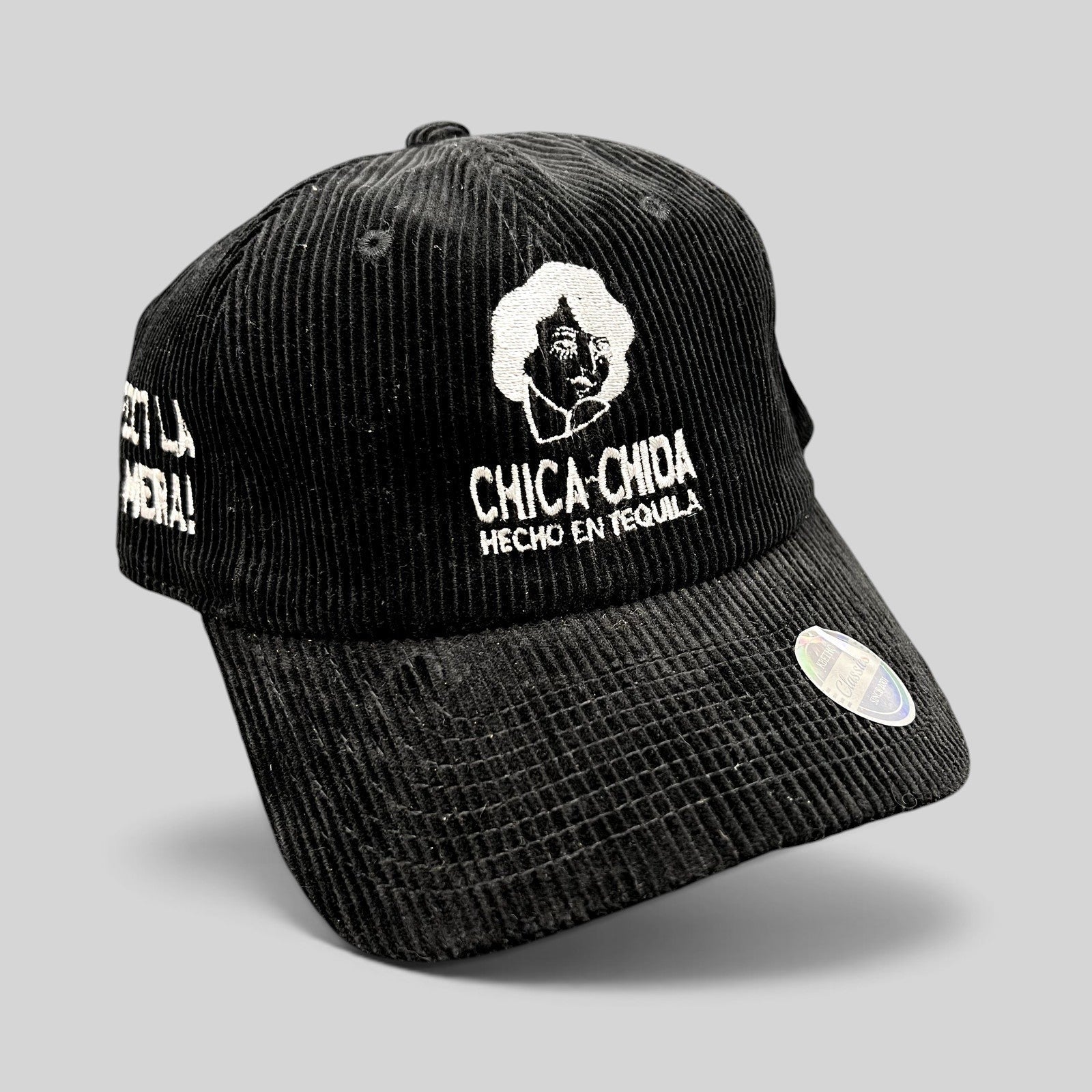 Raree Finds black corduroy strapback hat with white Chica~Chida Hecho en Tequila embroidery and brass buckle closure.