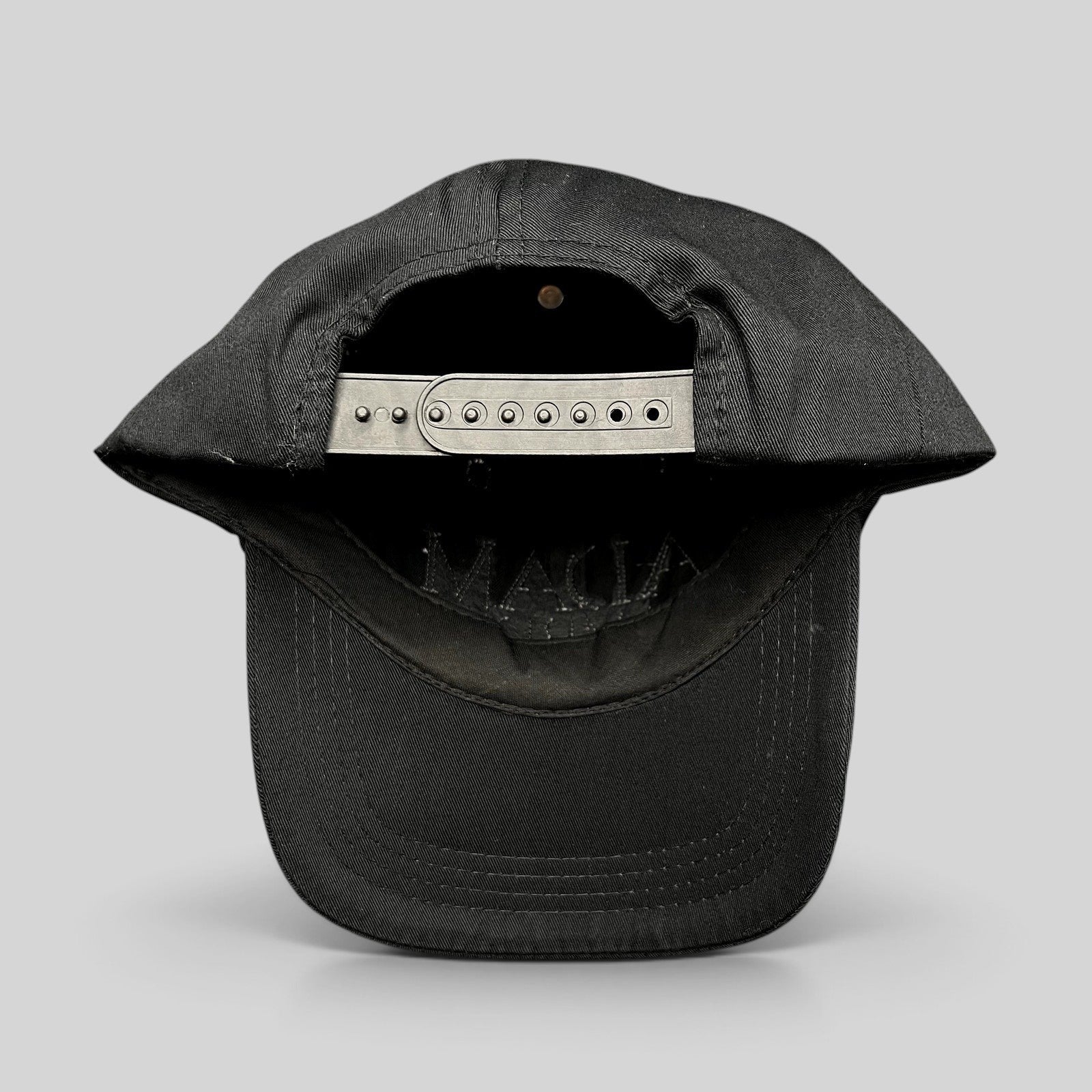 Raree Finds black cotton snapback hat showing the adjustable plastic strap closure and interior construction