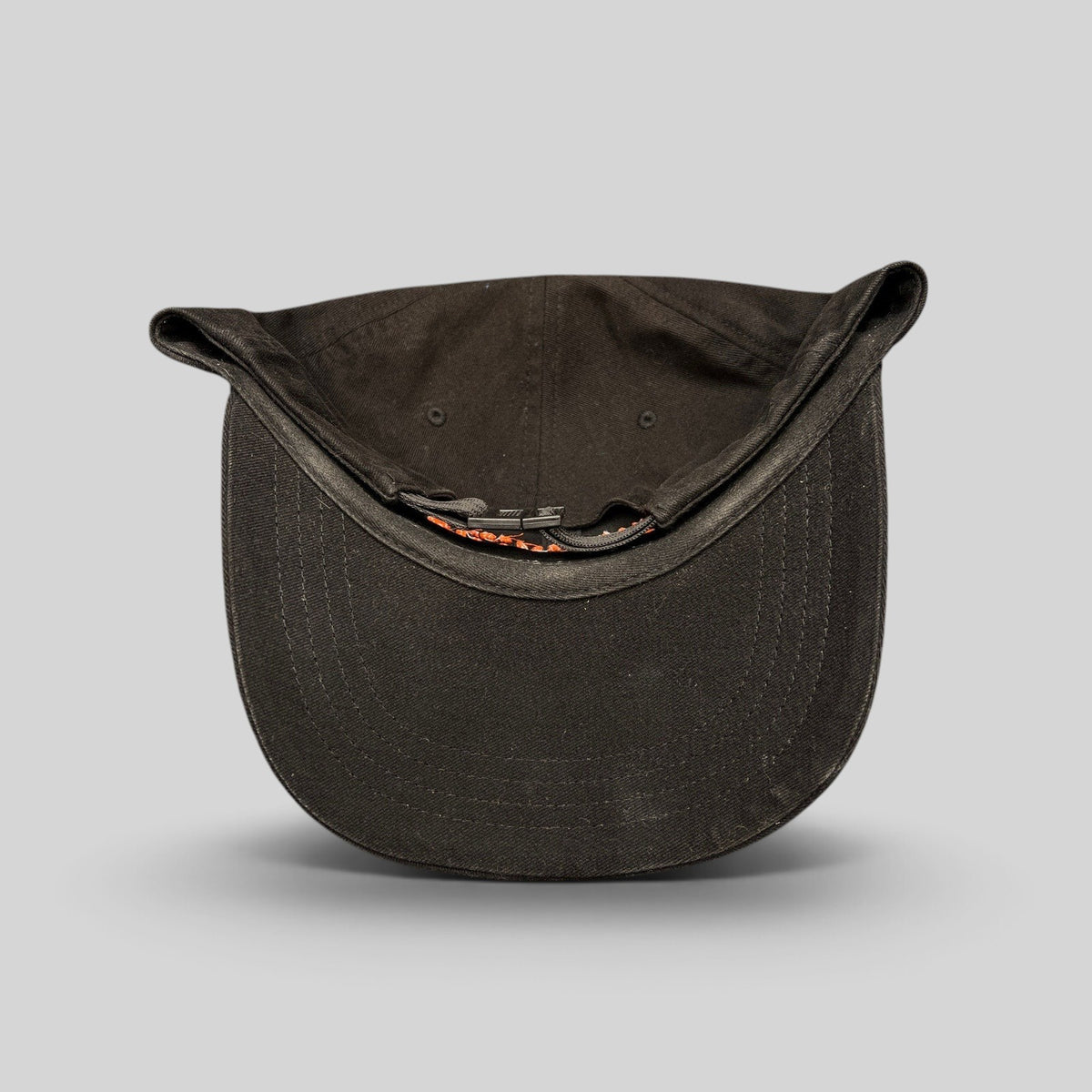 Raree Finds black cotton strapback hat with orange embroidered lettering and metal buckle closure