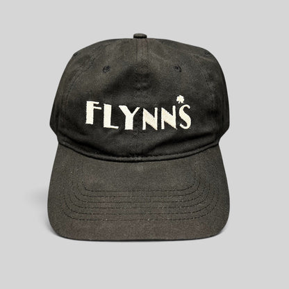 Raree Finds black unstructured strapback hat with white embroidered Flynn’s logo and shamrock accent on the front.