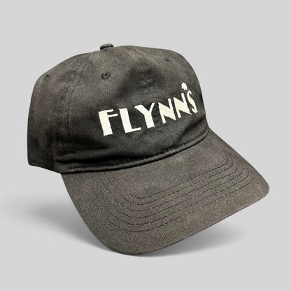 Raree Finds black unstructured strapback hat with white embroidered Flynn’s logo and shamrock accent on the front.